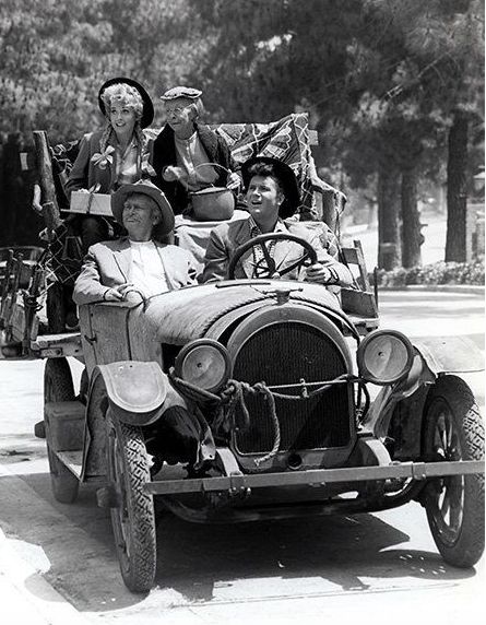 This may contain: black and white photograph of people riding in an old car